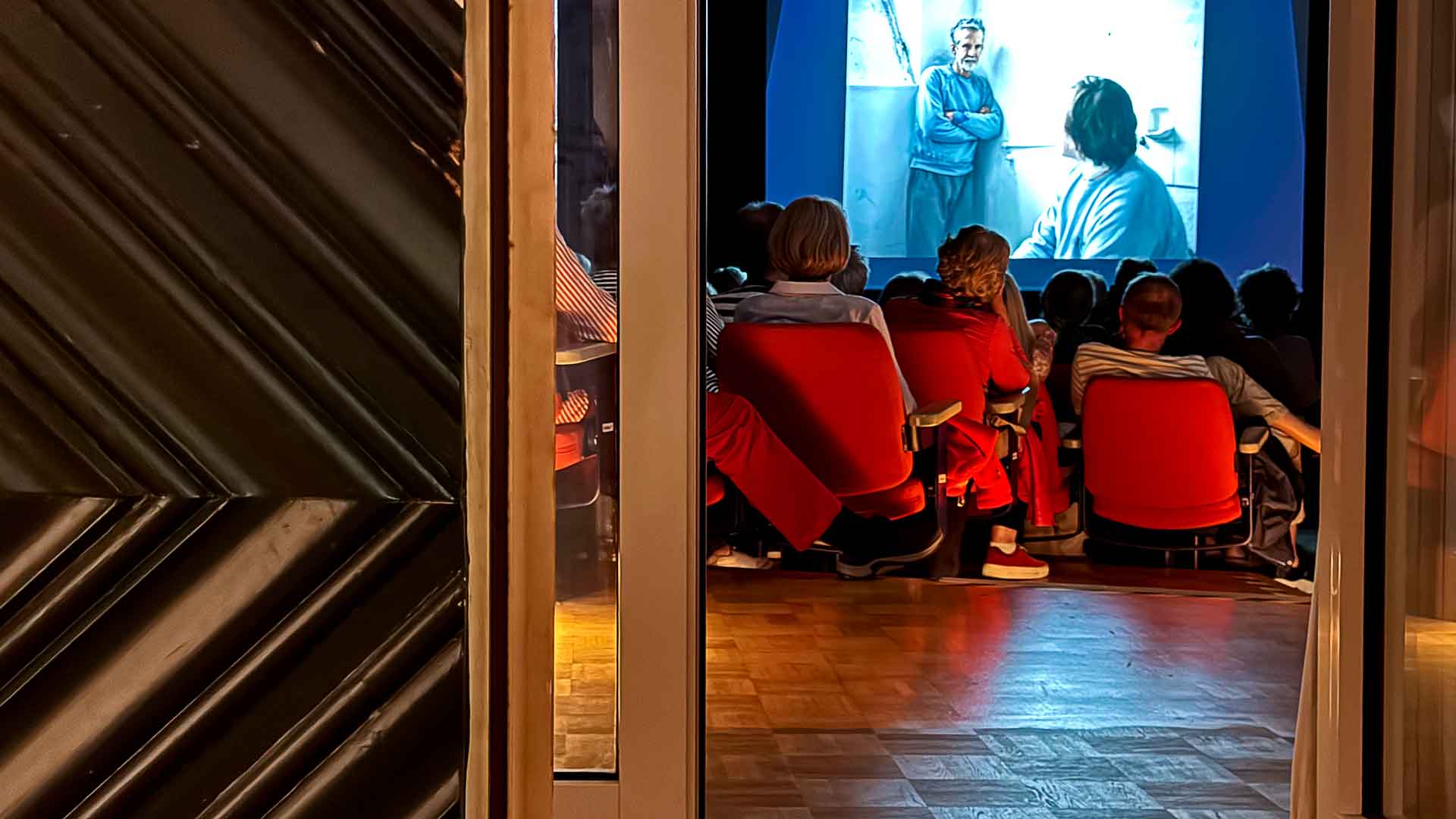 Blick durch Tür in den vollen Kinosaal des Kleinen Kinos am Weingarten
